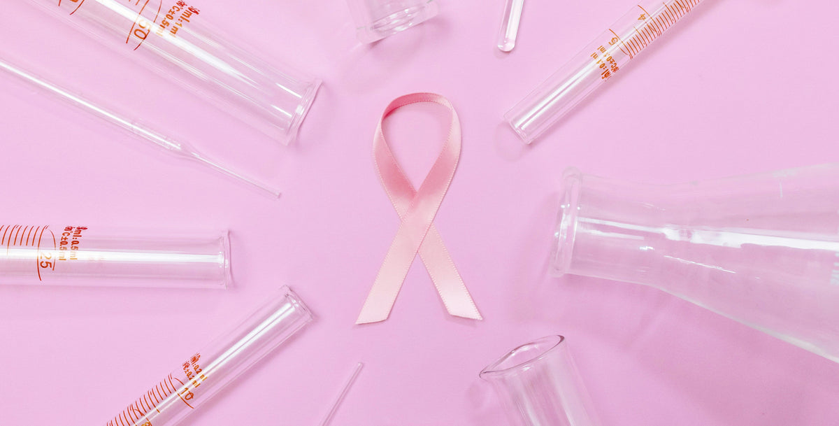 pink ribbon for breast cancer in a background with chemistry tubes around it